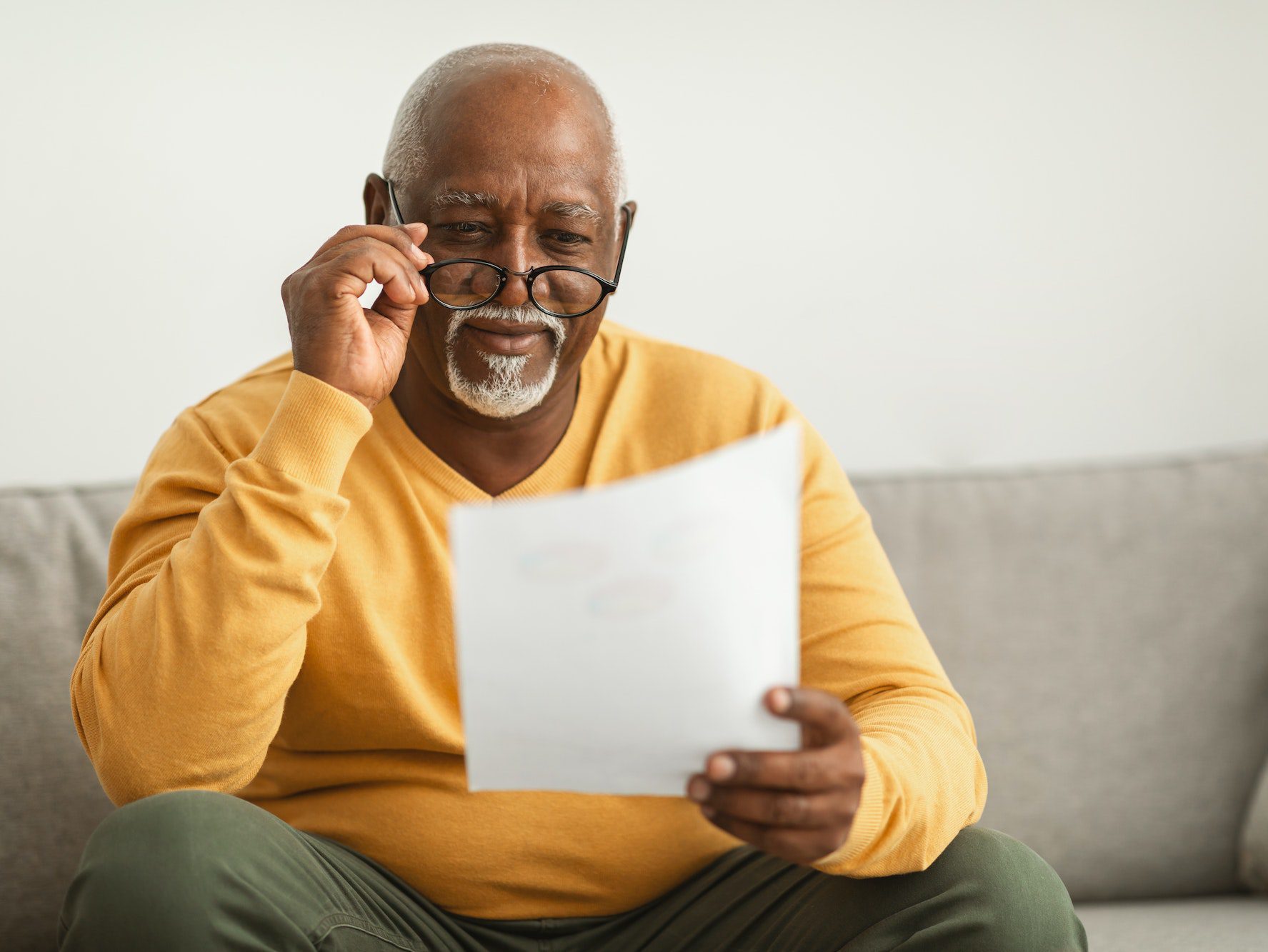 Contented Senior Black Man Reading Papers Wearing Eyeglasses At Home